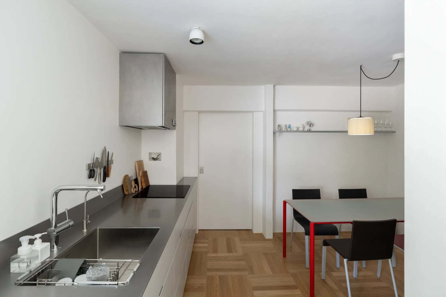 Dining area with a red-legged table, black chairs, a pendant lamp, and a refrigerator