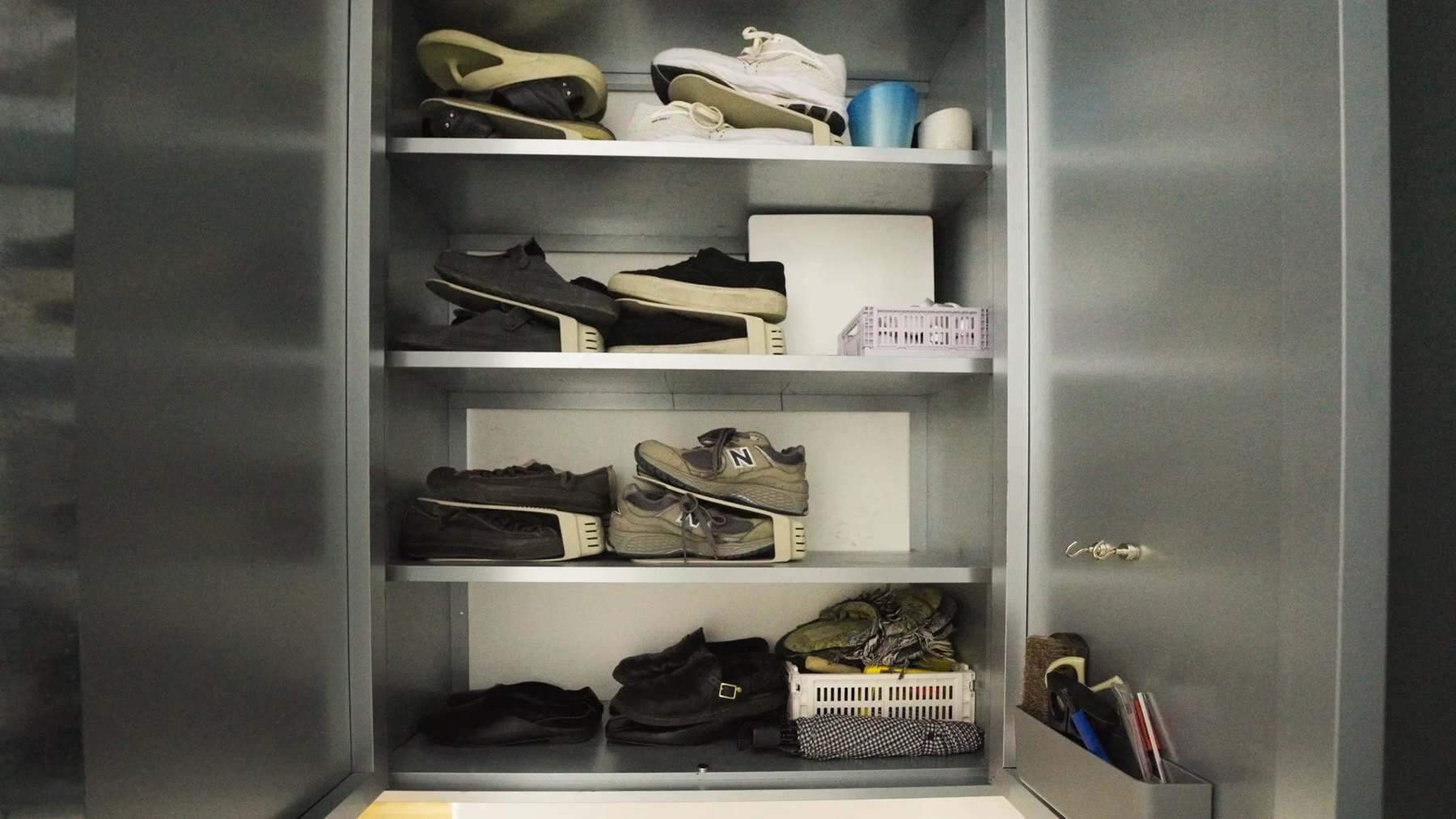 Open zinc shoe cabinet with shoes on shelves and bins below