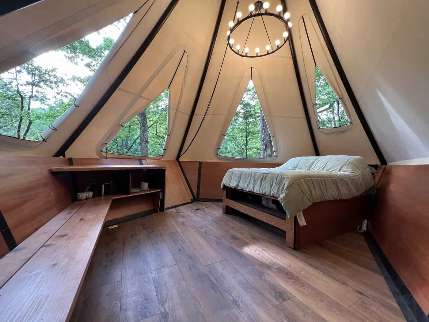 Wide treehouse interior with chandelier and panoramic forest windows