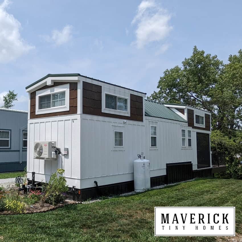 Maverick exterior: white board-and-batten with dark shaker upper, green metal roof, small deck on lawn