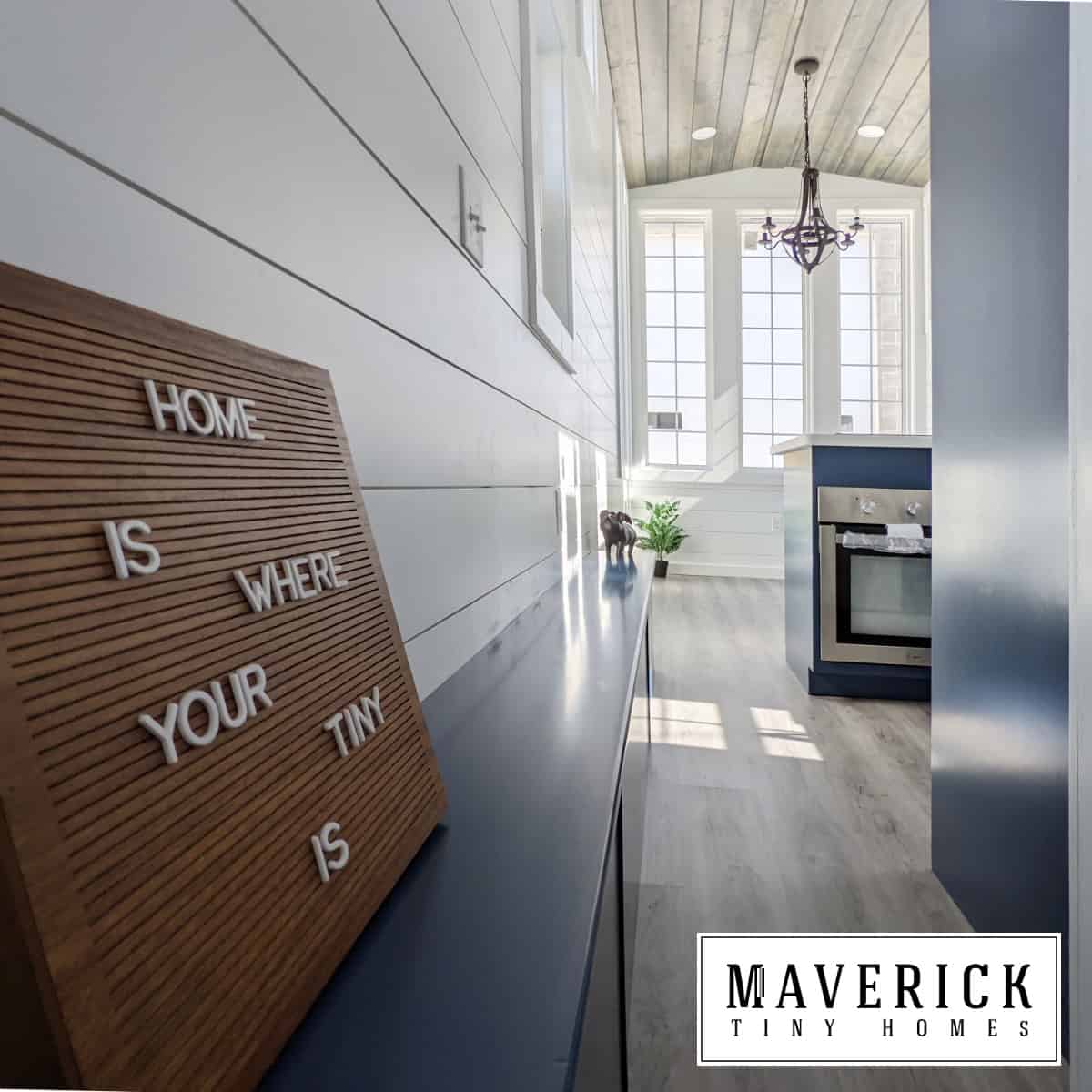 Maverick interior hallway: navy built-ins, wood-plank ceiling, letter board, window wall ahead