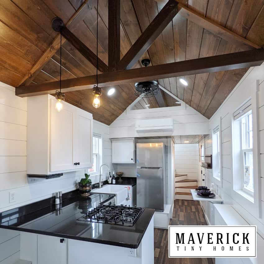 Maverick interior: vaulted dark-wood ceiling, granite-look counters, white shaker cabinets, stairs toward loft