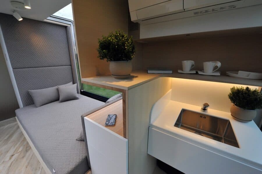 Compact tiny house kitchen and sleeping area with modern decor.