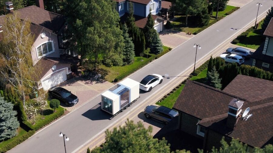 Compact microhome on wheels parked along a suburban neighborhood street.