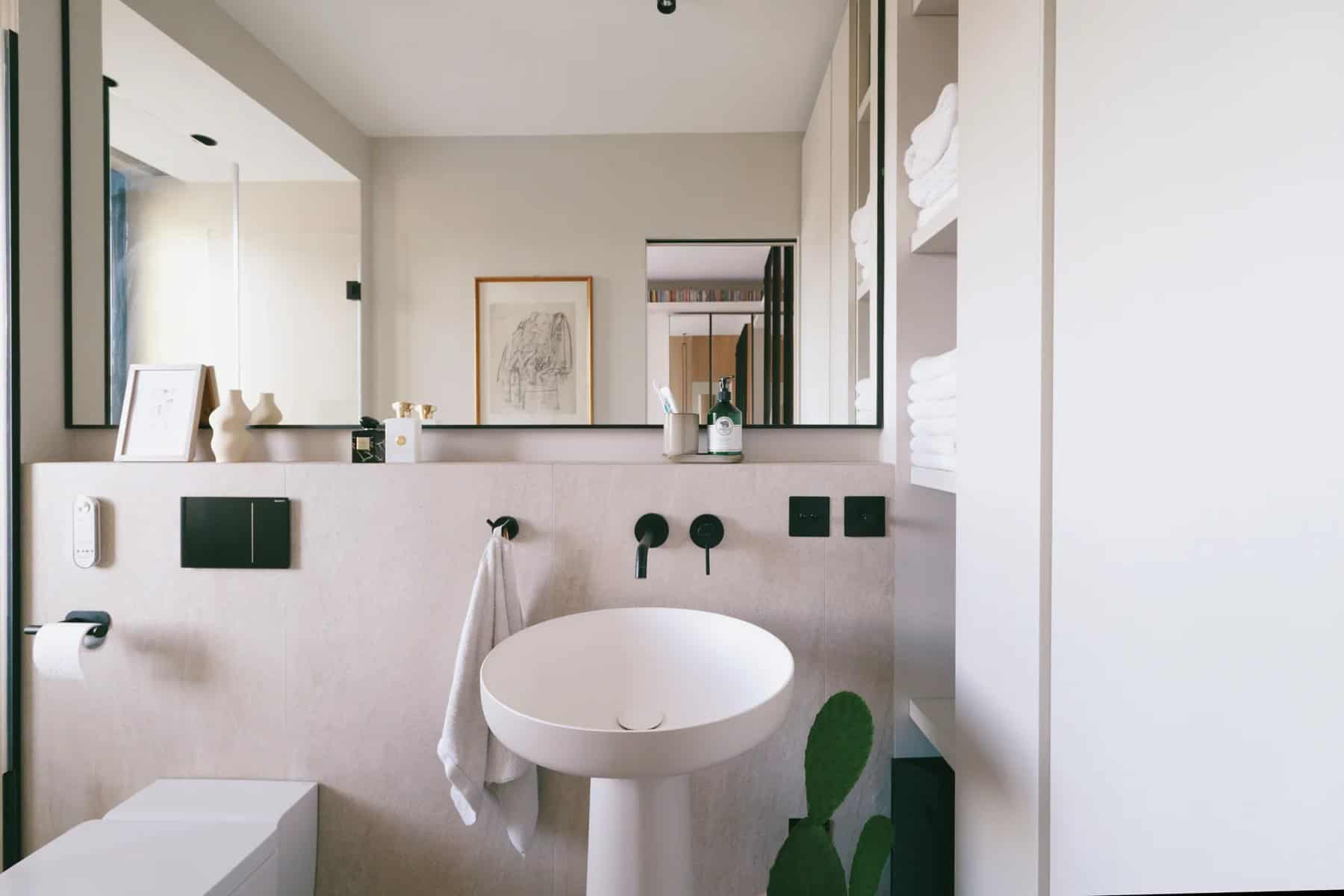 Bathroom with a sculptural white pedestal basin, mirror, and black fixtures