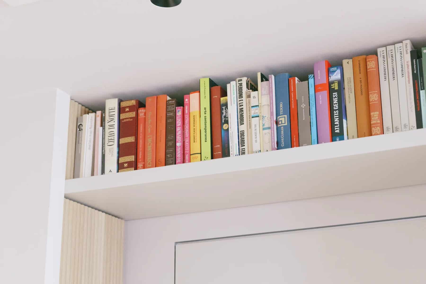 Ceiling-height bookshelf filled with colorful books above a doorway