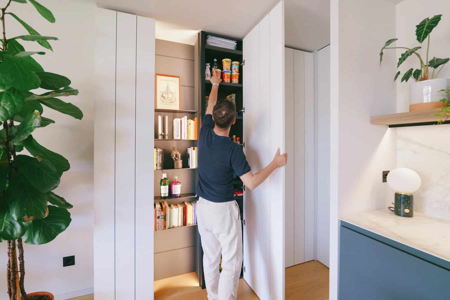 Ribbed white wall panel opened to reveal hidden pantry shelving