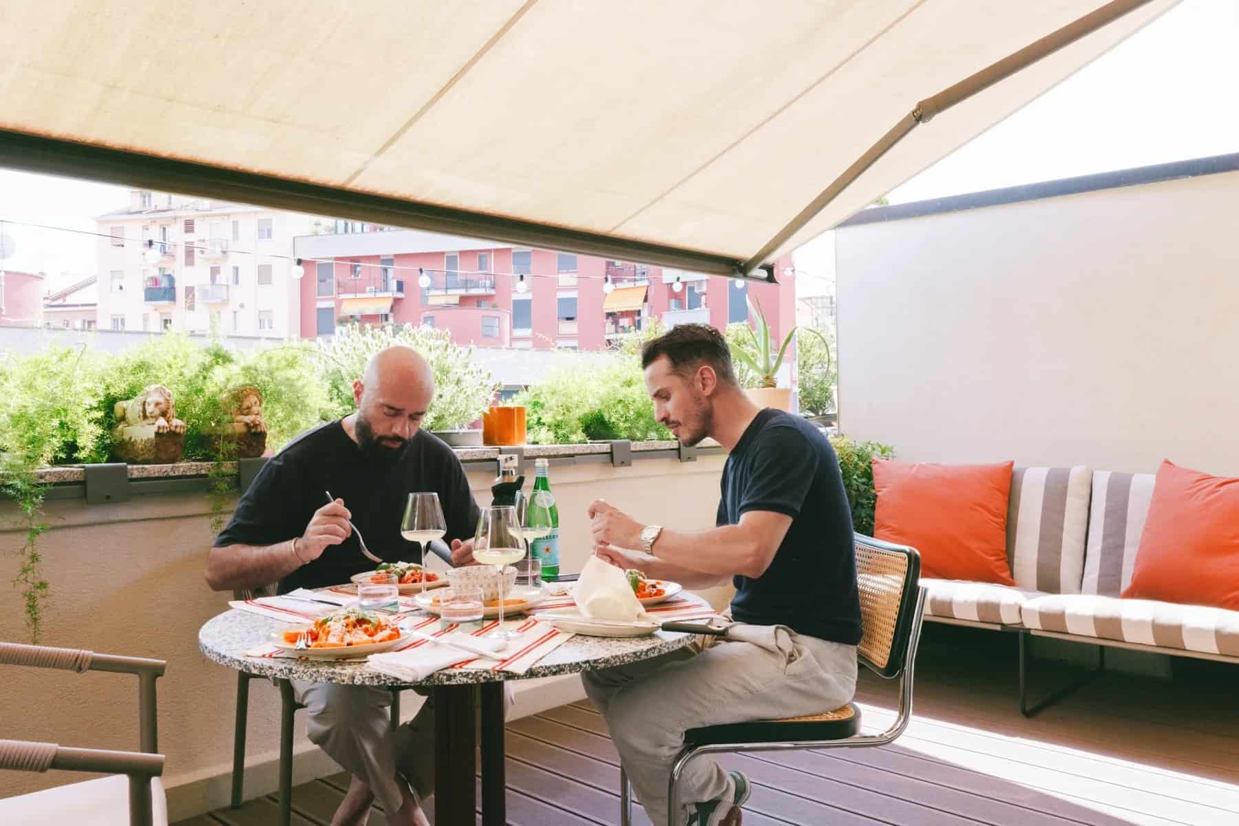 Two people dining at a round table on the terrace under an awning