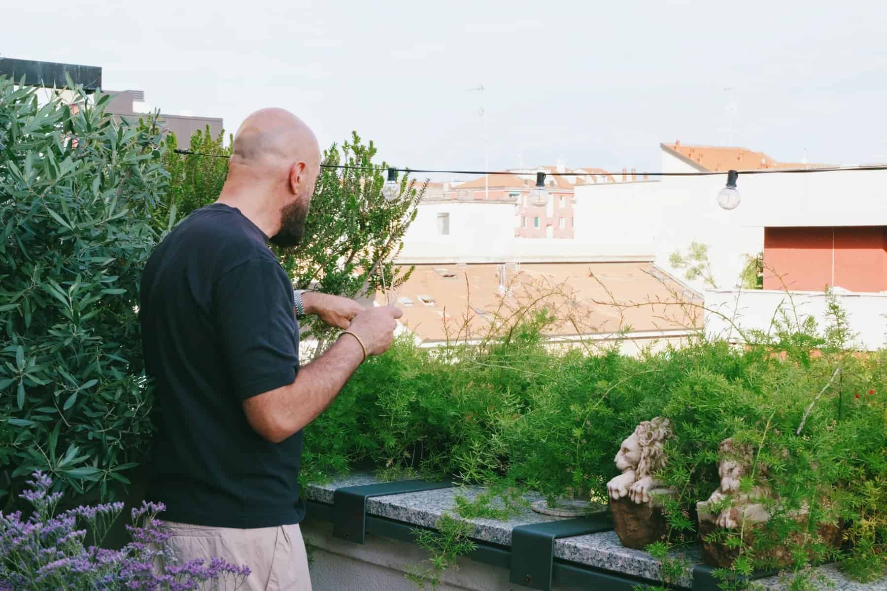 Simone tending planters filled with greenery along the terrace railing
