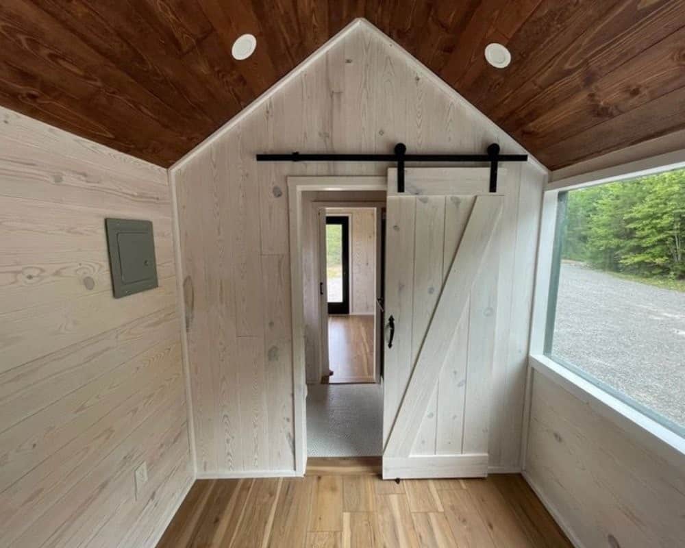 Whitewashed barn door leading to the bathroom in the Minimalist tiny house