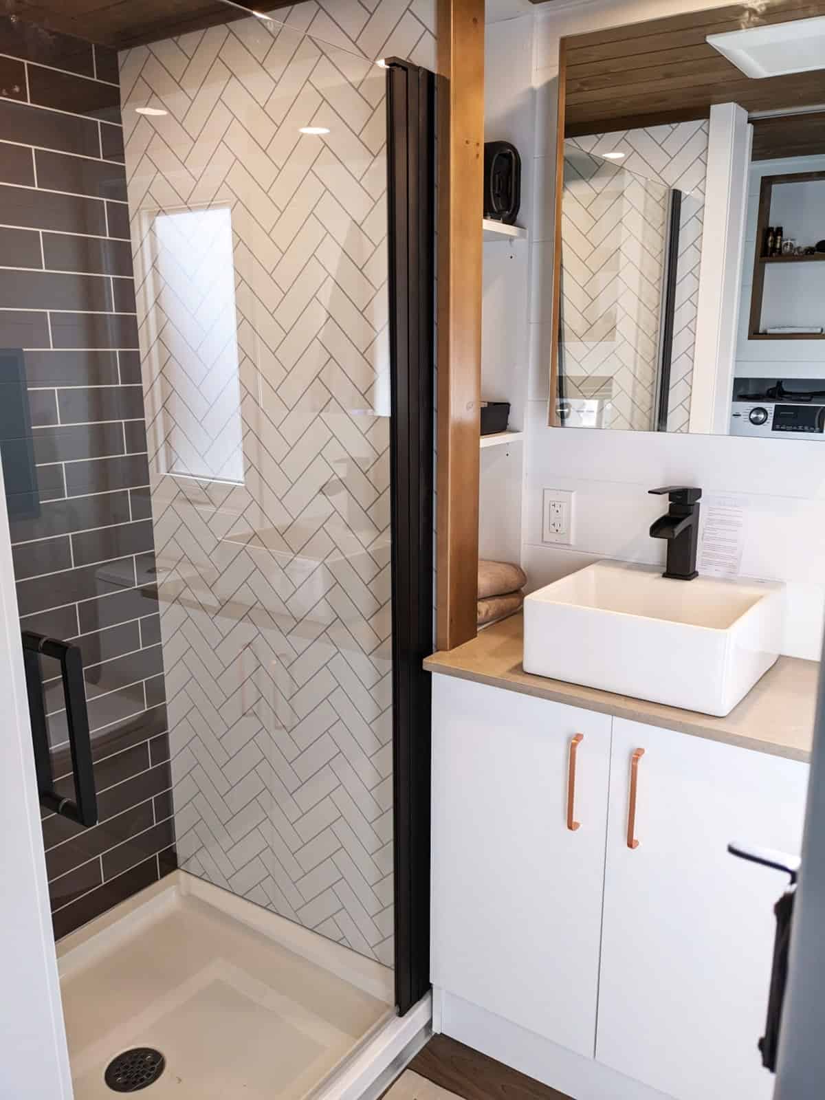 Tiny house bathroom with vanity sink, toilet and glass enclosed shower