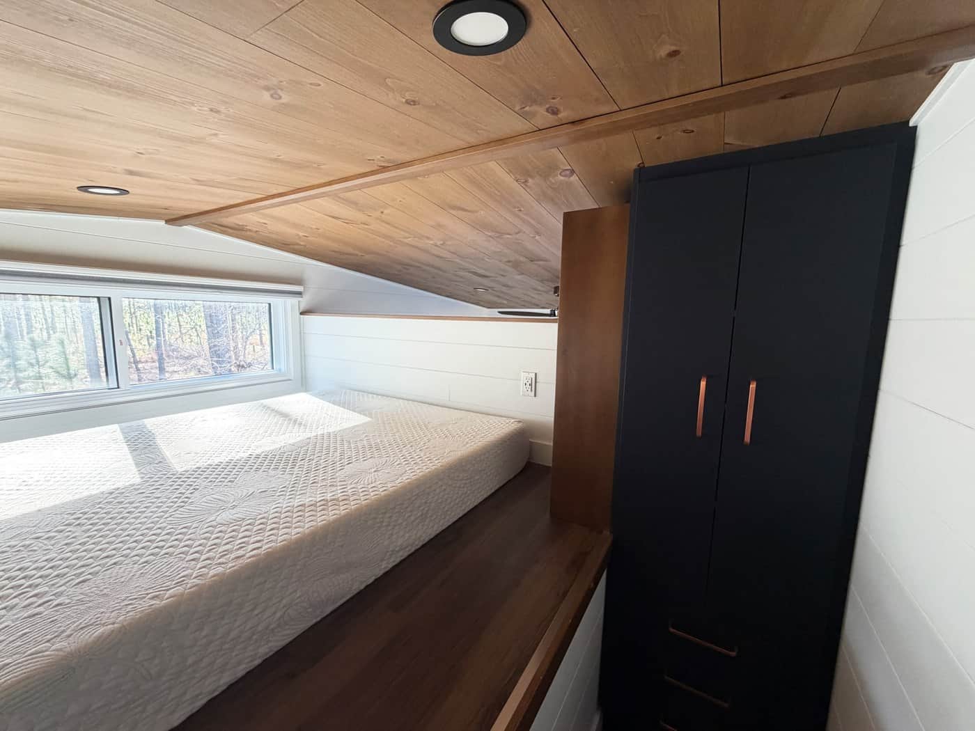 Loft bedroom with a queen bed and a tall navy closet