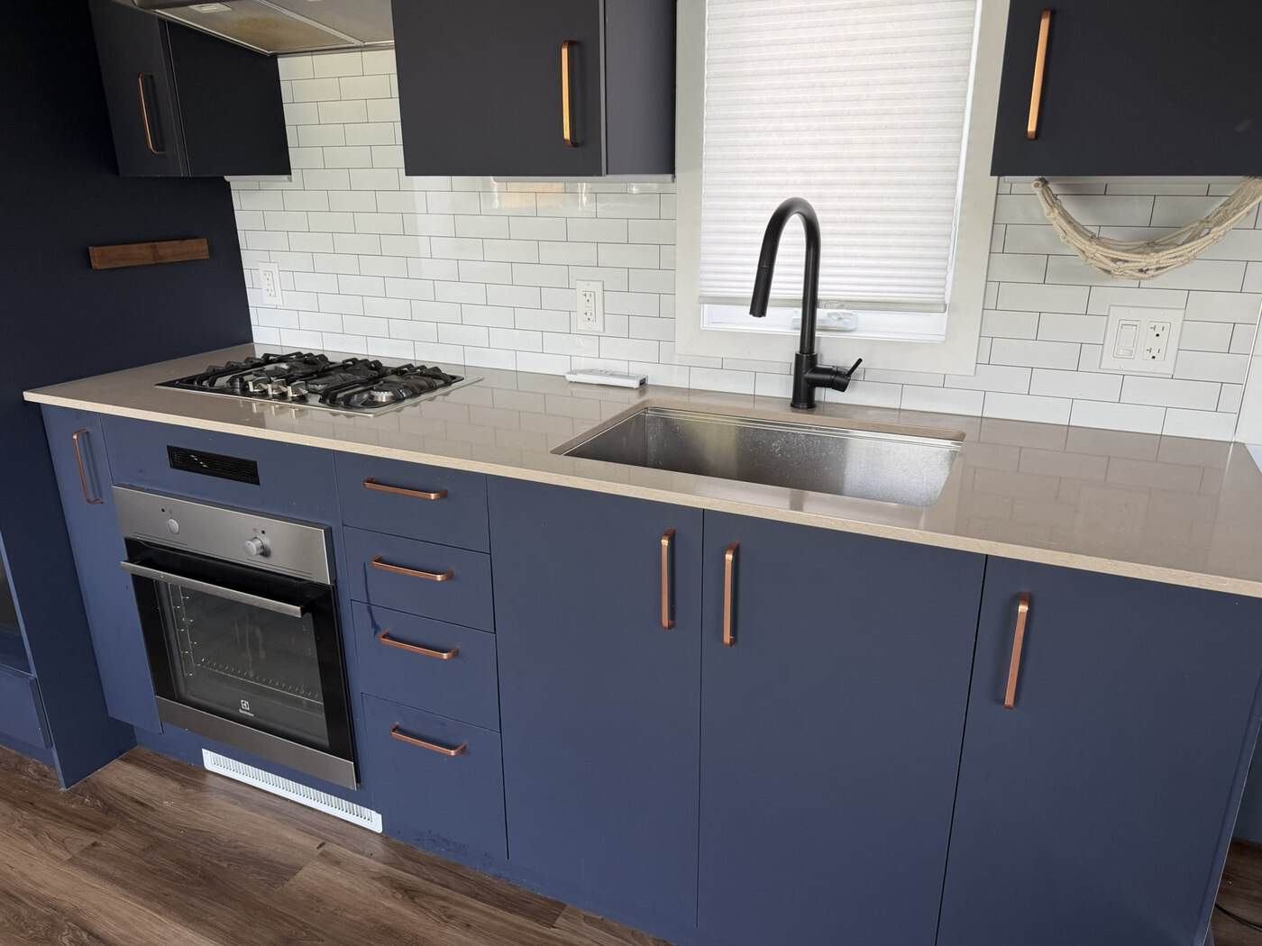 Navy galley kitchen with gas cooktop, wall oven and white subway tile backsplash