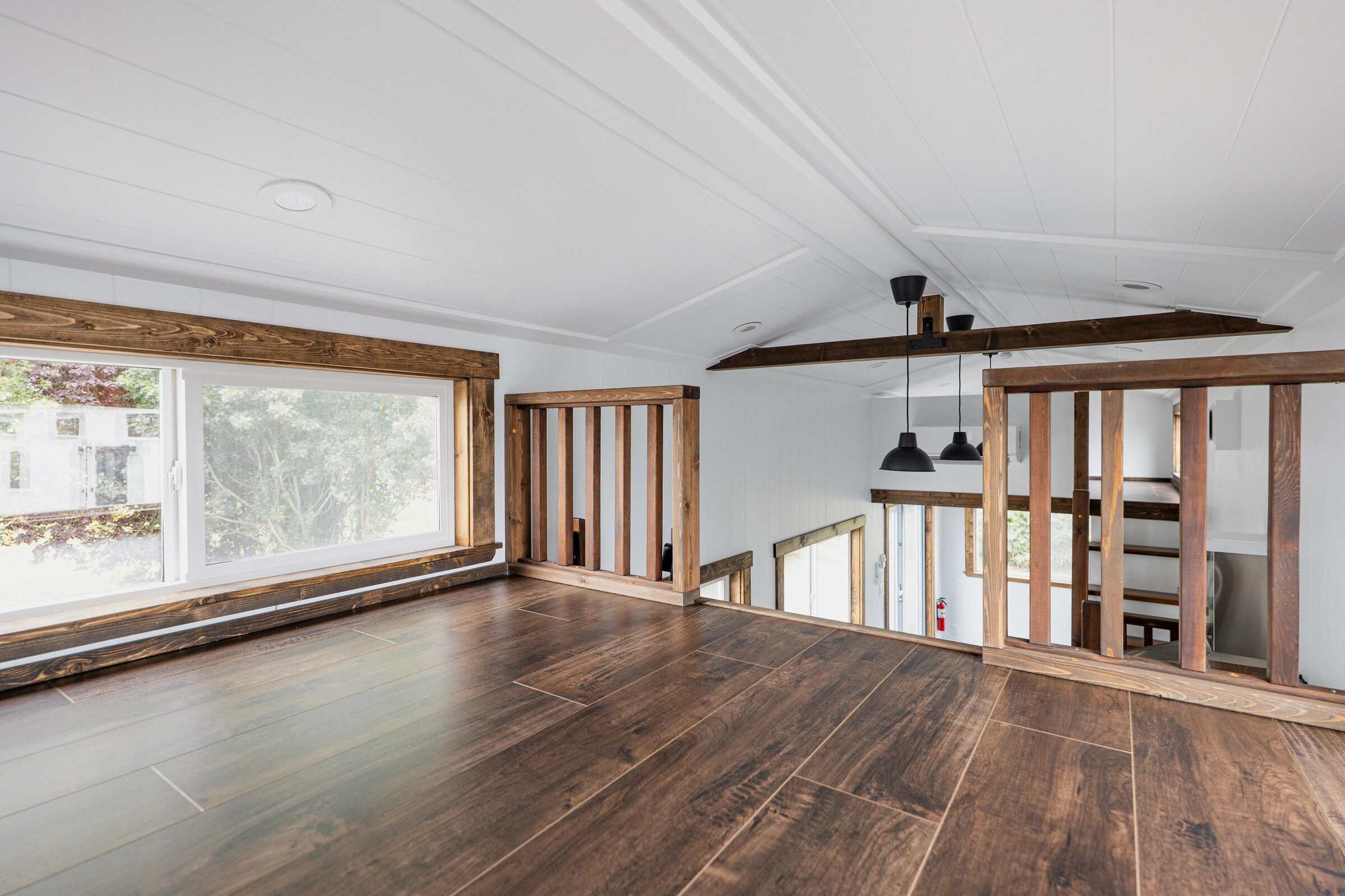 From an Arctic loft: white shiplap, dark wood rail and floor, pendant lights over the living run, second loft stairs beyond