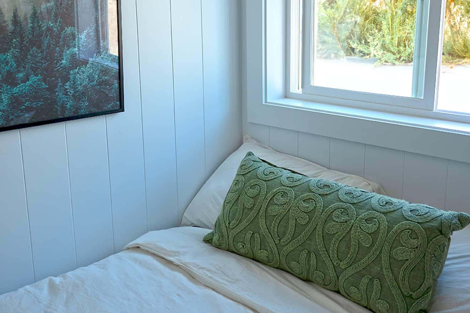 Main-floor bedroom: white shiplap, large window, white bedding, standing height — Jason ADU, Delta BC
