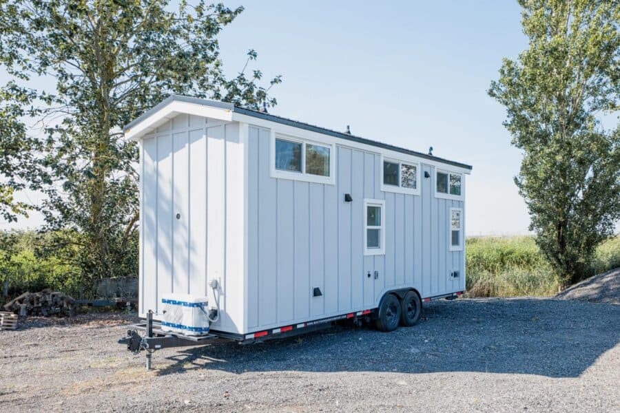 Mint STR 26 tiny house on a dual-axle bumper-pull trailer: light grey vertical siding, white trim, dark standing-seam roof, high loft windows, white mini-split on the tongue