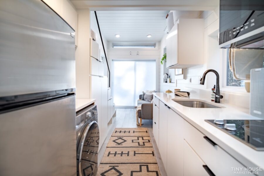Shipping container home kitchen with sleek white cabinets and modern appliances.