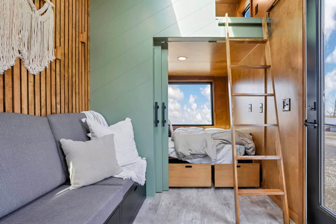 Modern Tiny Living Catalina interior: living volume toward first-floor master bedroom with loft ladder and king-sized loft above