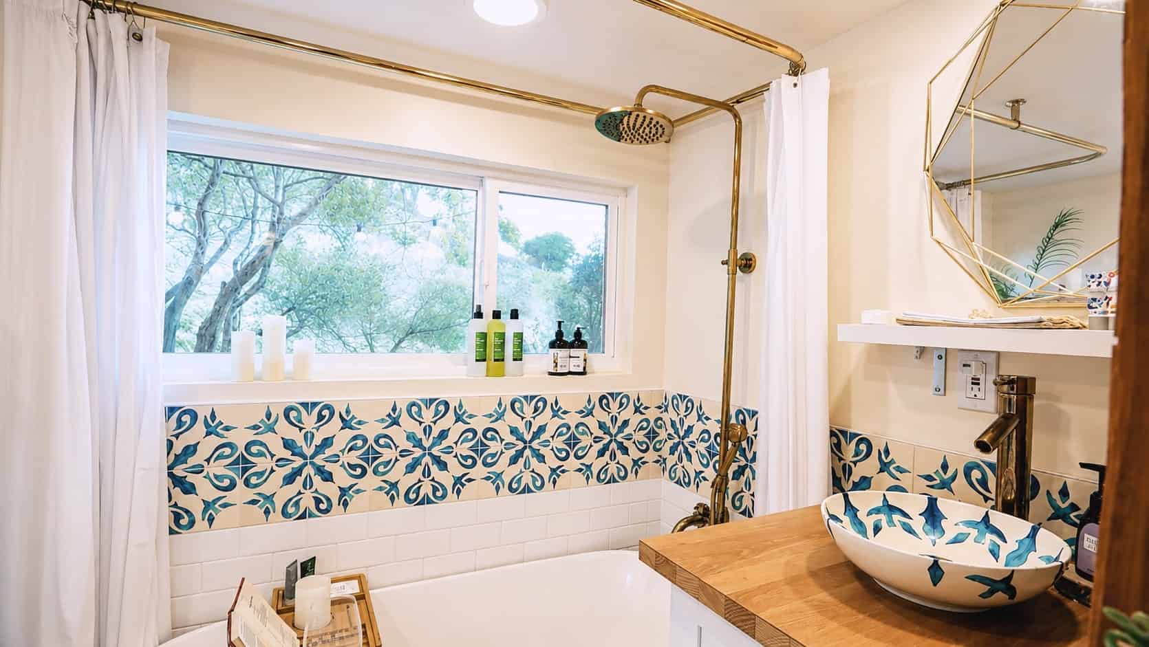 Bathroom with painted vessel sink, blue tile, and brass fixtures in the tiny house