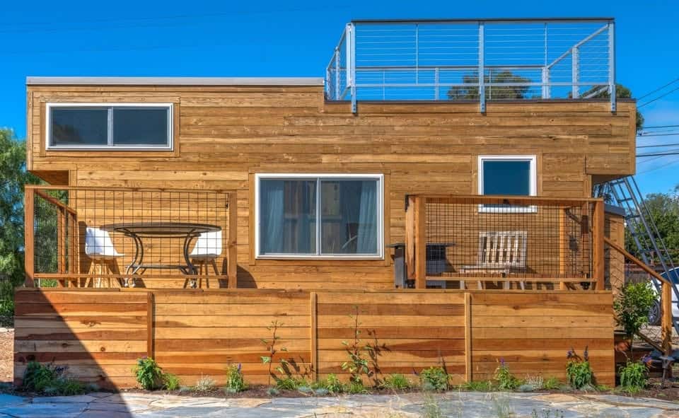 Cedar sided Moroccan tiny house on wheels with rooftop deck and porches