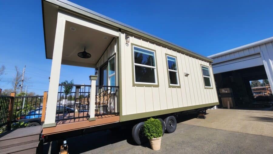 Modern tiny mountain house on wheels with porch and large windows.