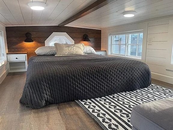 Sleeping loft of the Mustard Seed Sprout with a bed, dark wood headboard wall, octagonal window, and built-in nightstands