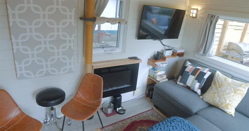 Living area with a sofa, fireplace, chairs, and a wall-mounted TV