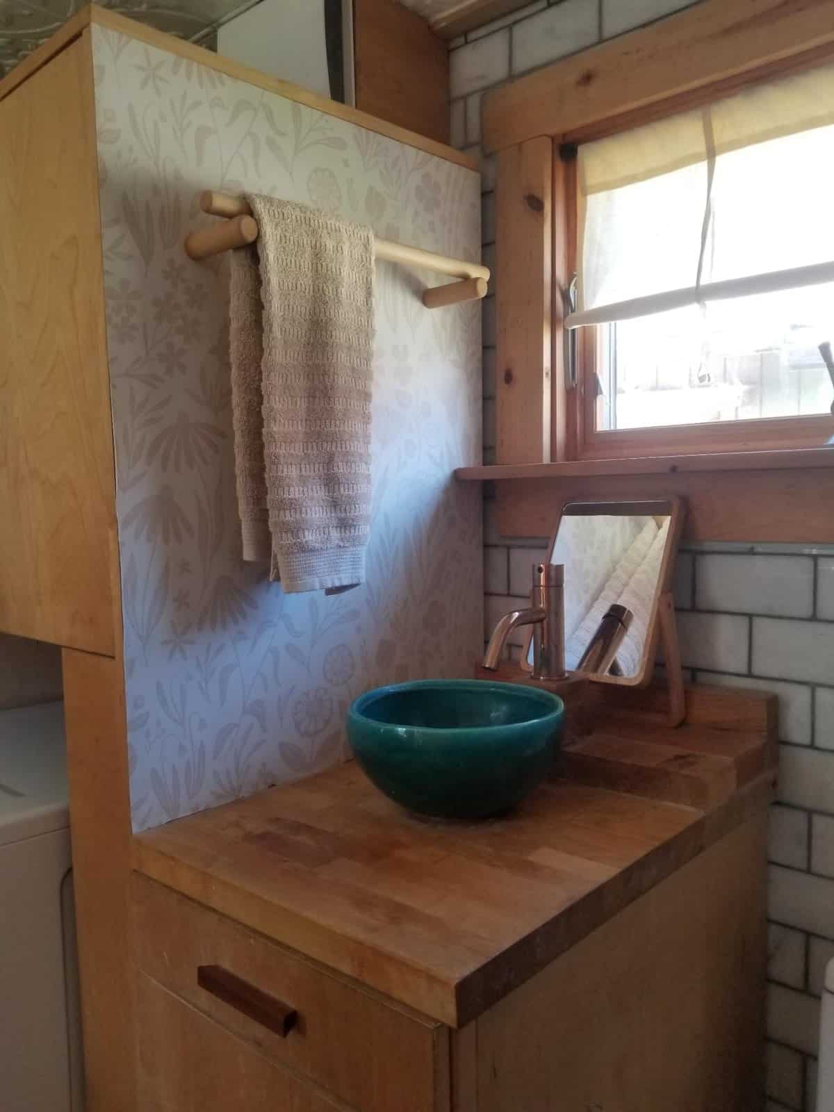 Bathroom vanity with a handmade green crackle ceramic vessel sink and wood counter