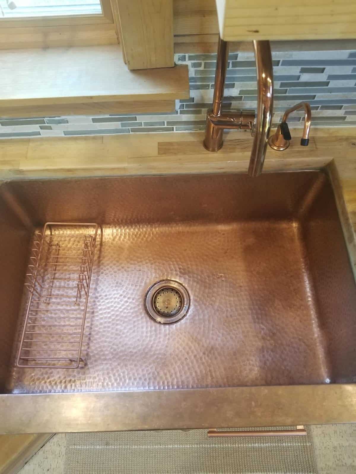Solid hammered copper farmhouse kitchen sink set in birch butcher block counter