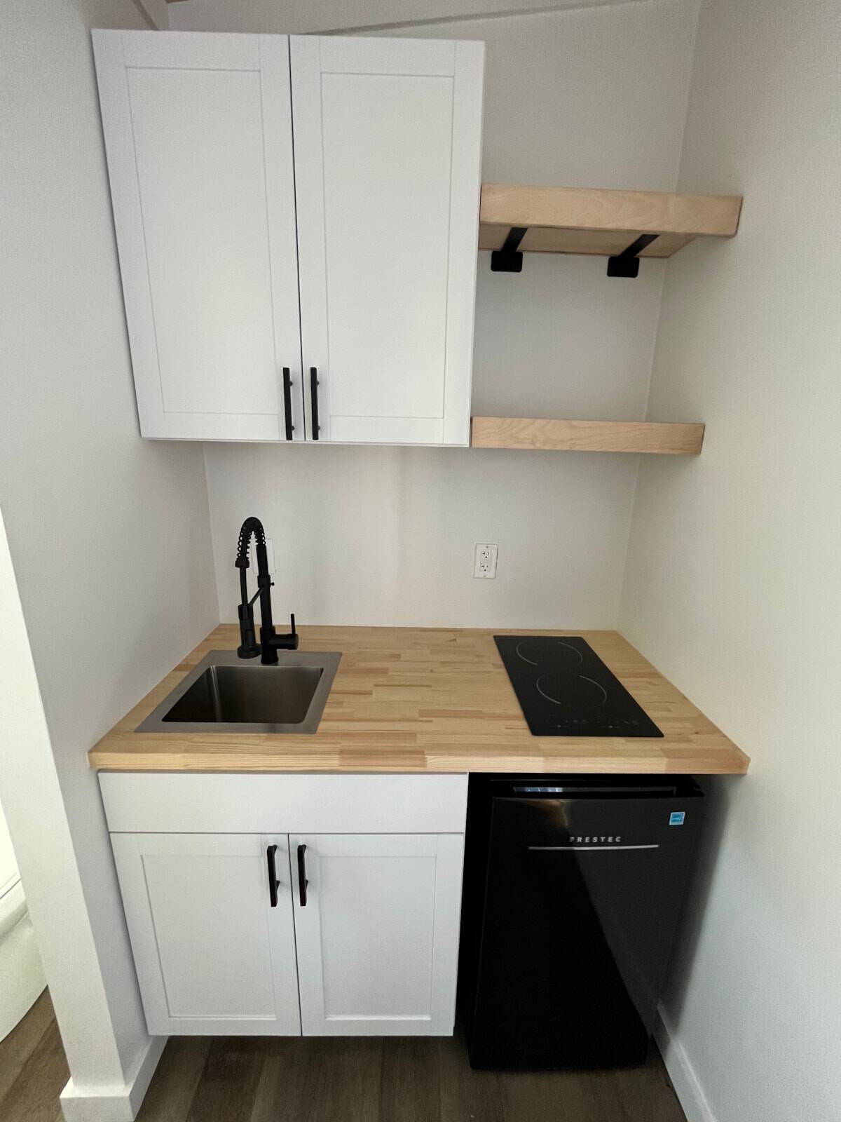 Kitchenette with butcher block counter, cooktop, and mini fridge in the tiny house