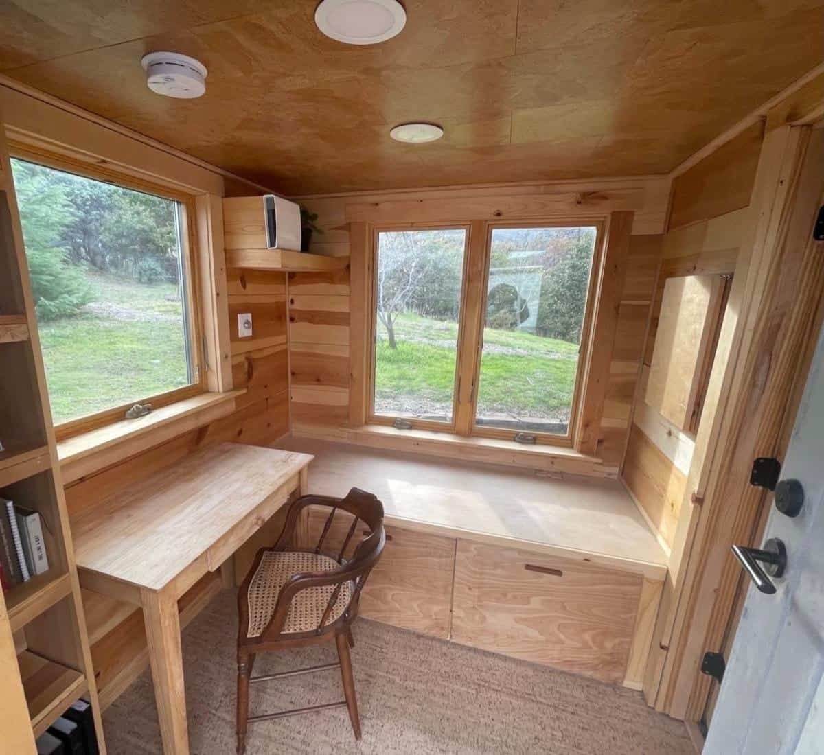 The tiny house office showing its own exterior door and built-in window seating