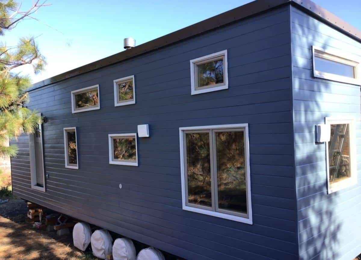 Navy blue NOAH certified tiny house on wheels for sale in Oregon on a four-axle trailer