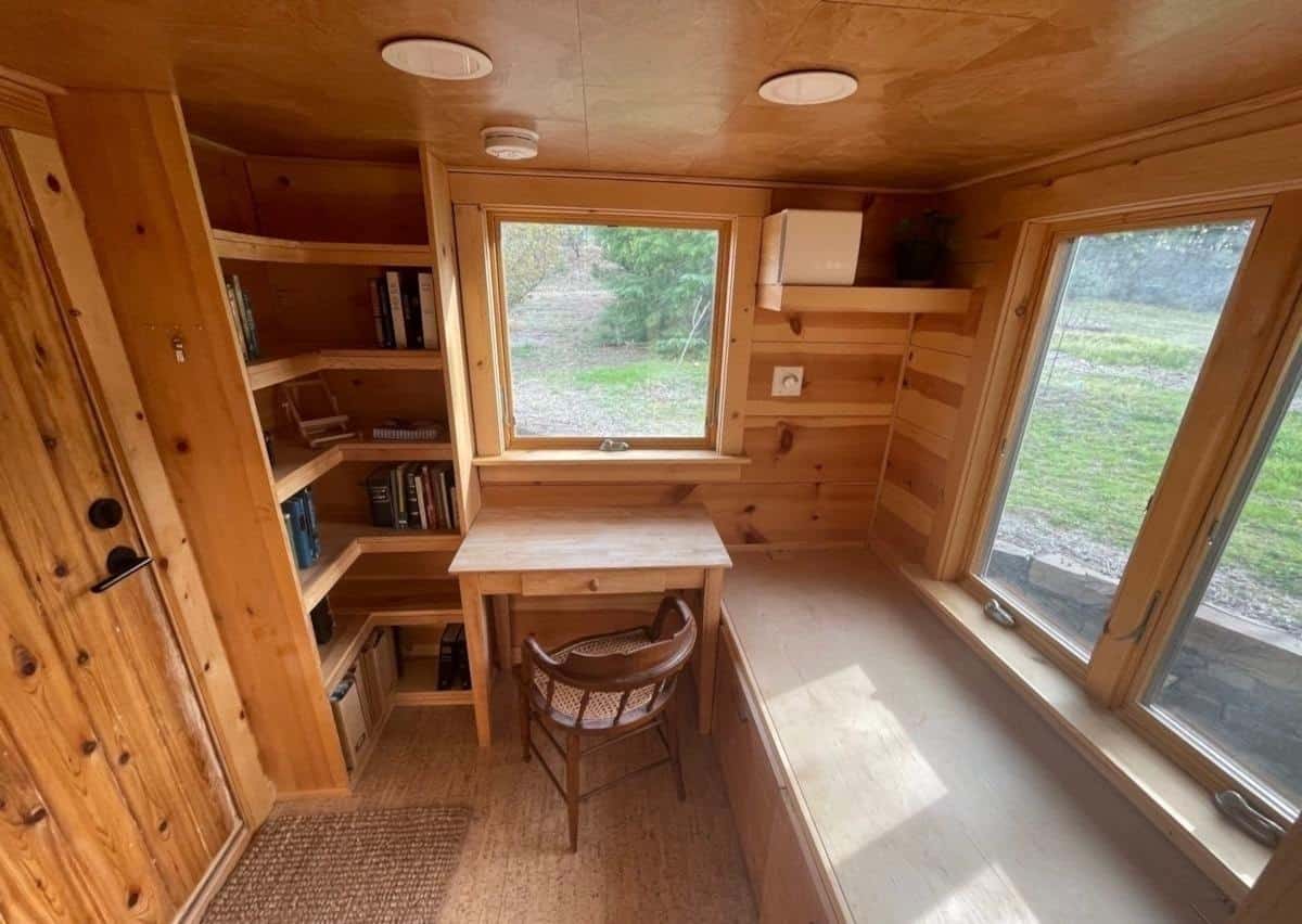 Private office inside the tiny house with built-in bookshelves, desk and window bench