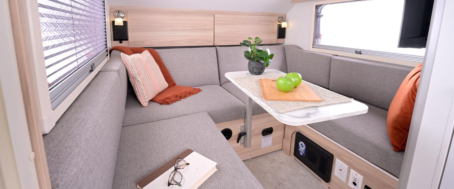 U-shaped grey dinette in the 2026 nuCamp TAB 320 with a marble-look pedestal table, reading lights, and side windows