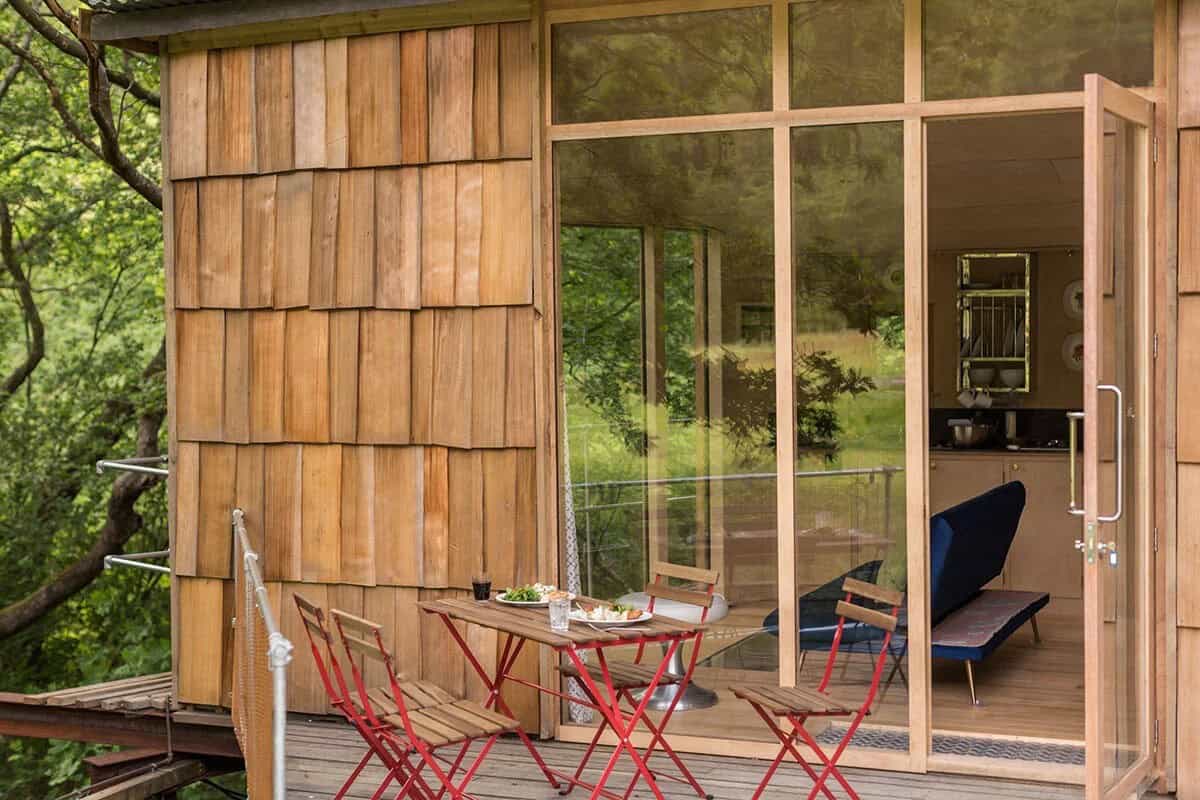 Deck with red folding chairs and table outside the treehouse cabin's glass doors