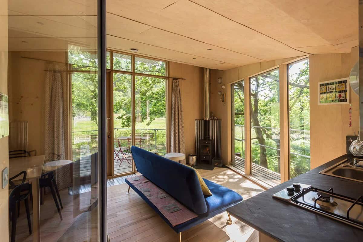 Living room with blue sofa, wood-burning stove, and glass to the canopy