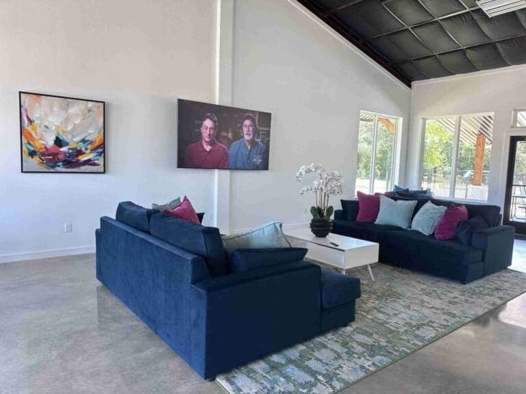 Clubhouse lounge with navy sofas, a vaulted ceiling, and a wall-mounted TV at The Oaks on 37 in Mount Vernon, Texas