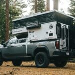 OEV Back Country pop-up raised on a GMC Sierra in a pine forest