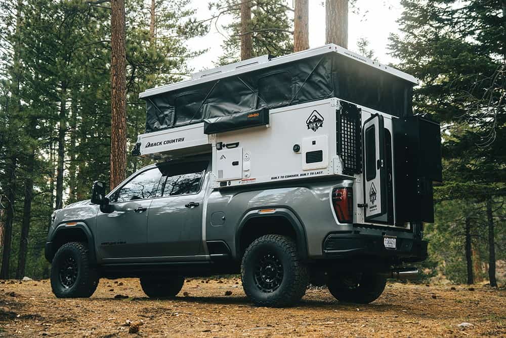 OEV Back Country pop-up raised on a GMC Sierra in a pine forest