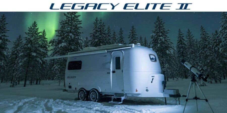 2027 Oliver Legacy Elite II twin-axle fiberglass travel trailer parked in snow under northern lights