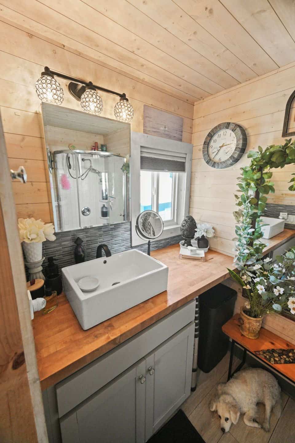 Bathroom vanity with a white vessel sink, butcher block counter and round mirror