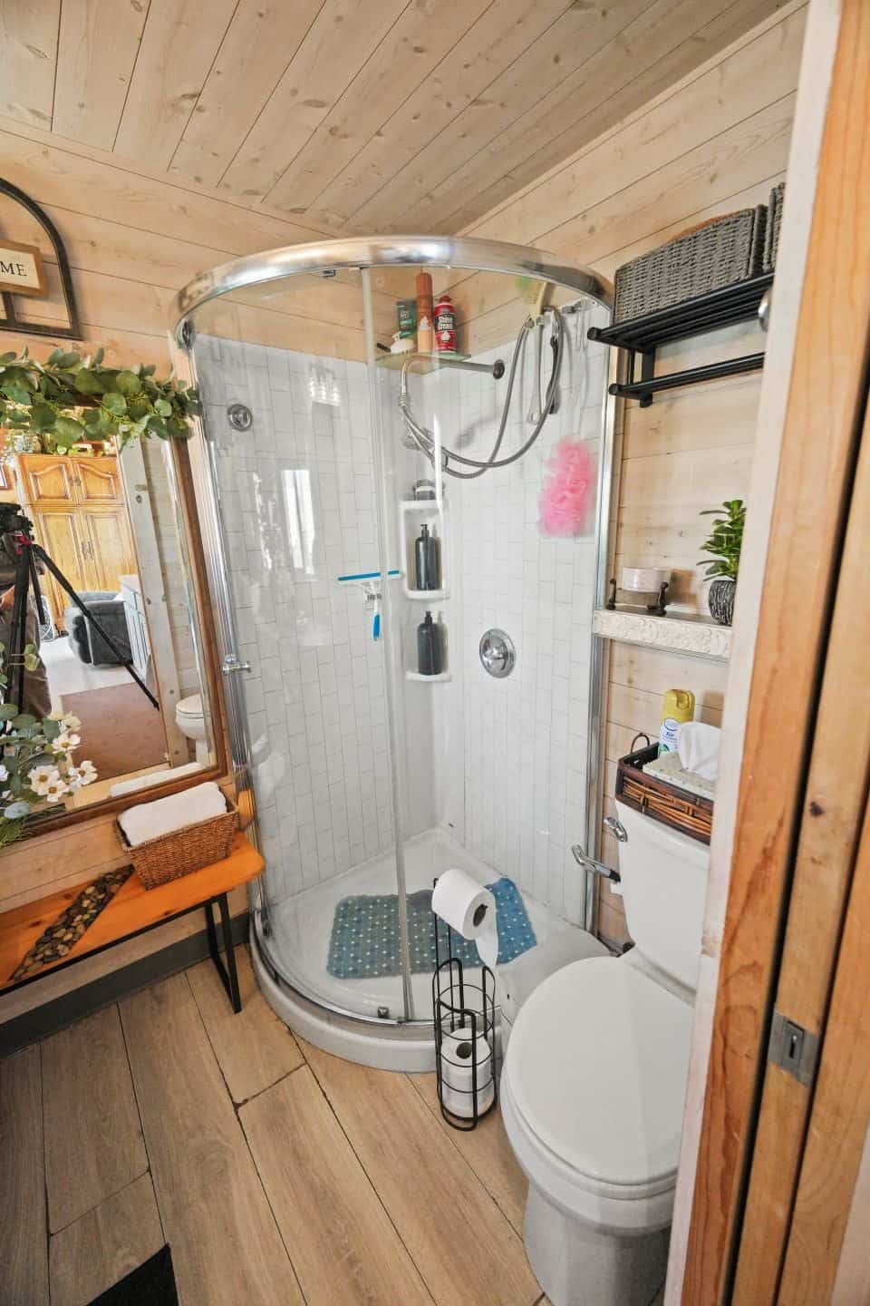 Tiny house bathroom with a curved glass corner shower and flush toilet