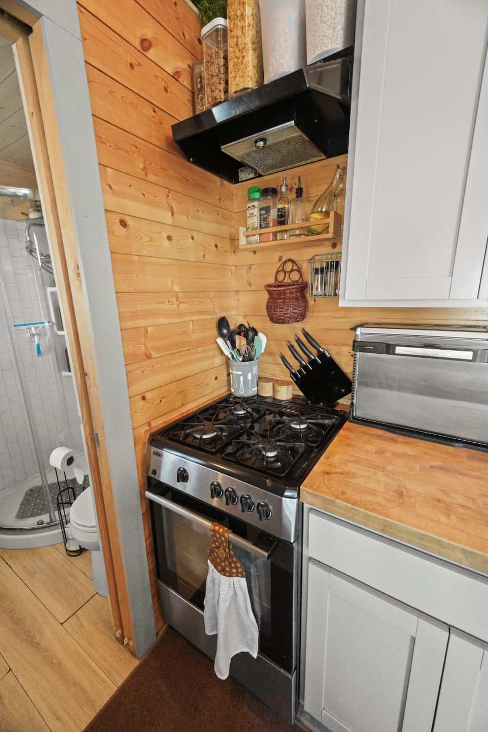 Four-burner gas range with oven and range hood next to butcher block counters