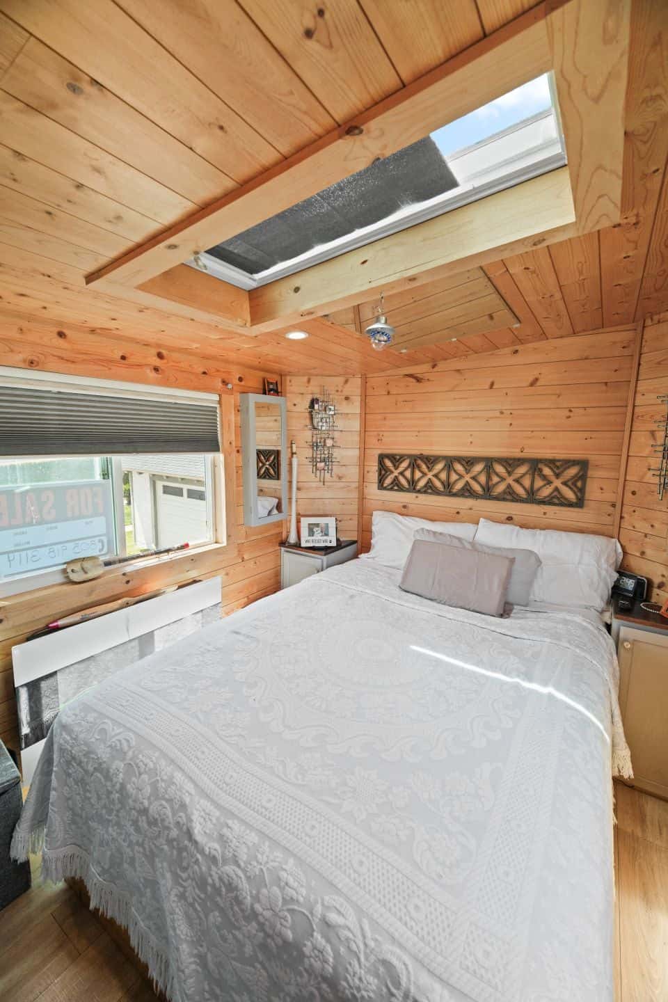 Queen bed in the gooseneck bedroom under a skylight with pine walls and ceiling
