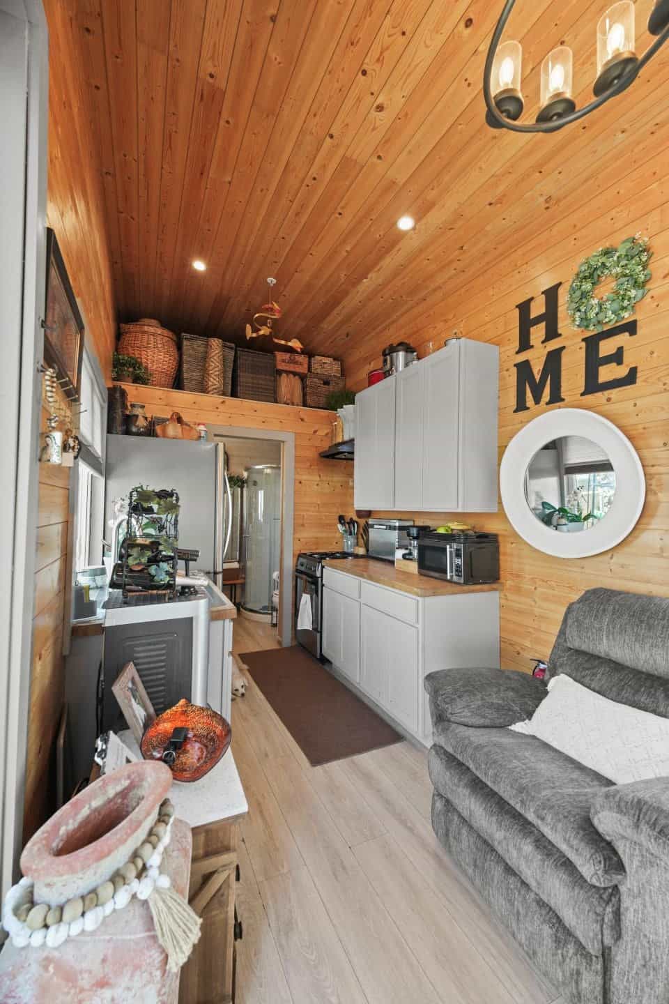 Pine-paneled living room with a gray recliner looking toward the galley kitchen