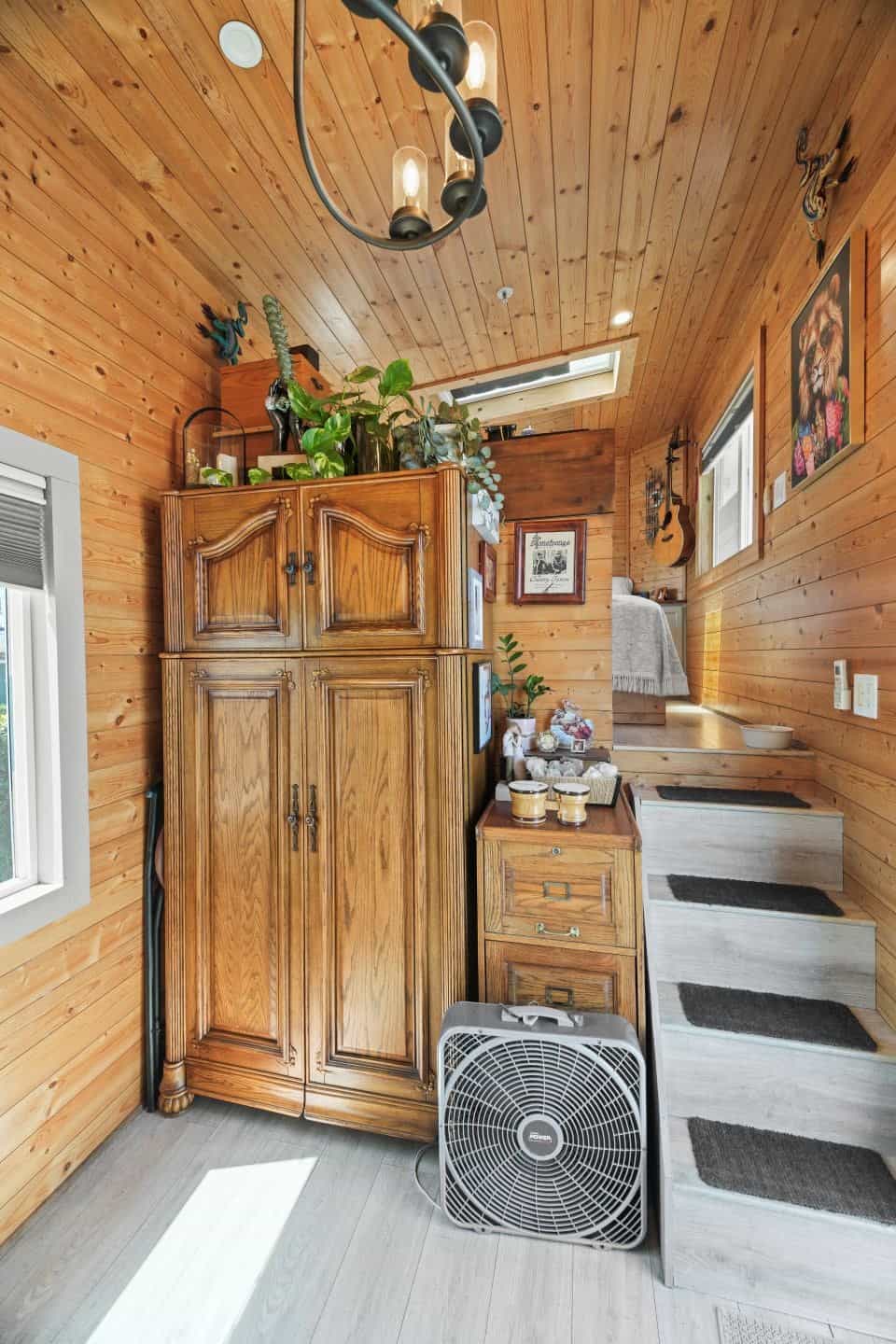 Wide stairs leading up to the gooseneck bedroom beside a wooden armoire