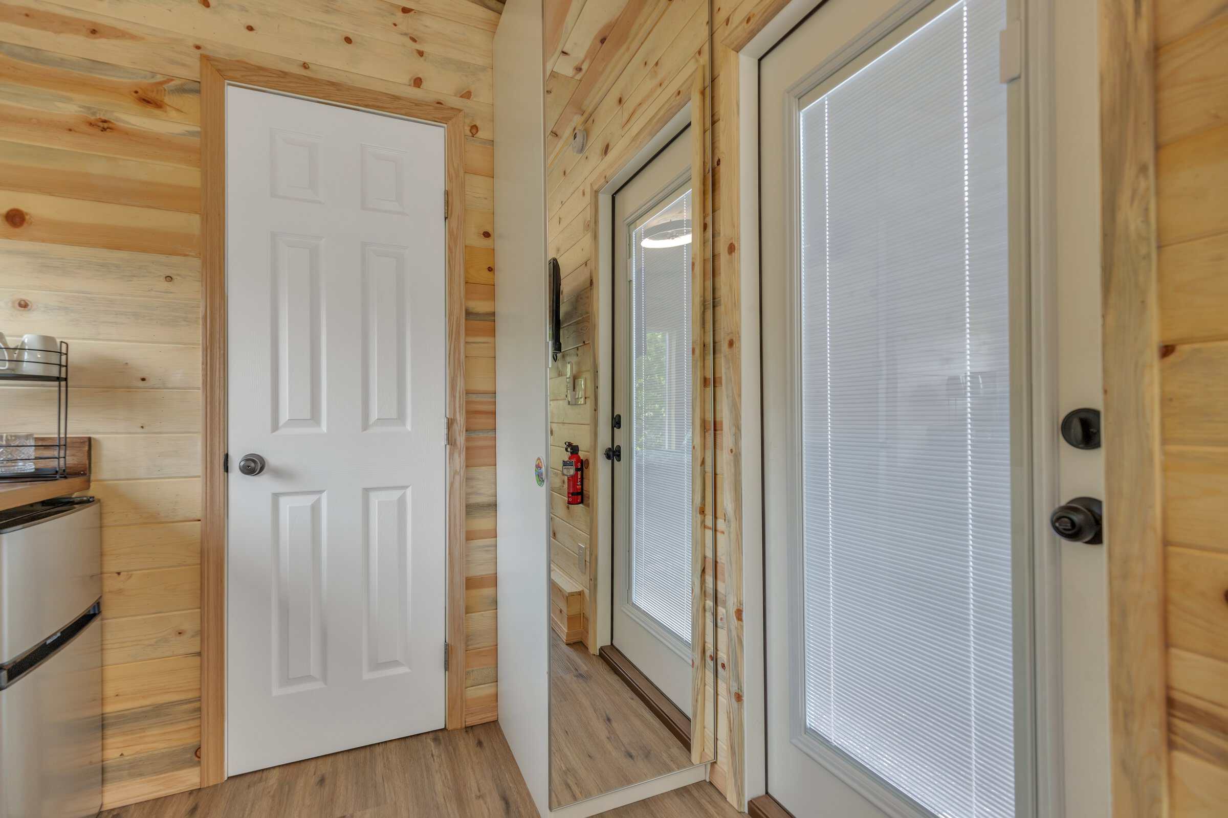 Pacifica Model X entry edge: mirrored wardrobe, glass door with blinds, kitchen cabinets and butcher-block beyond