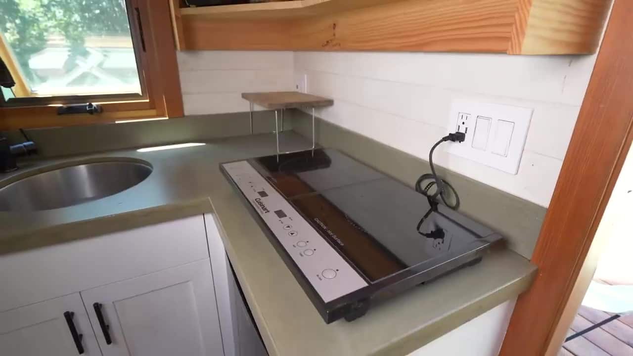 Olive-gray custom concrete kitchen counters with a round sink, black faucet, and two-burner induction cooktop