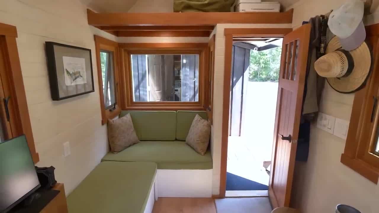 L-shaped sage guest couch under windows looking onto the deck and workshop