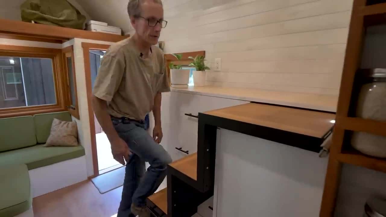 Pull-out drawer stairs extended as Patrick climbs toward the loft